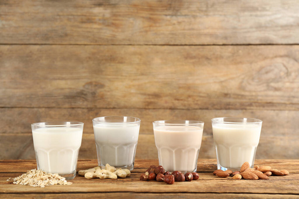 Different vegan milks and ingredients on wooden table. Space for text - Φωτογραφία, εικόνα