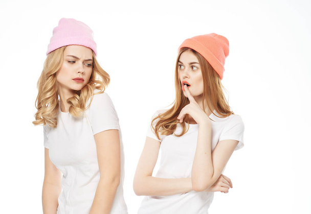 dos mujeres en camisetas blancas sombreros en el fondo de la luz de comunicación de moda cabeza - Foto, imagen