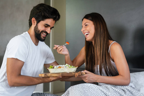 Good morning. Healthy breakfast in bed. Young beautiful couple in love spending time together - Foto, afbeelding