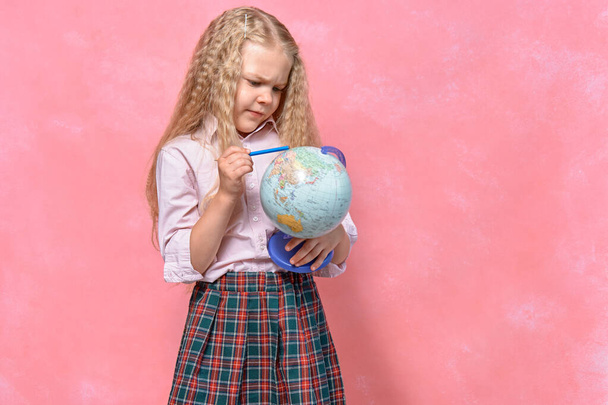 schoolgirl holds planet globe in her hand. pink background - Zdjęcie, obraz