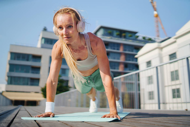Mid adult woman doing push-ups outdoors in city, exercise and healthy lifestyle concept. - Fotoğraf, Görsel