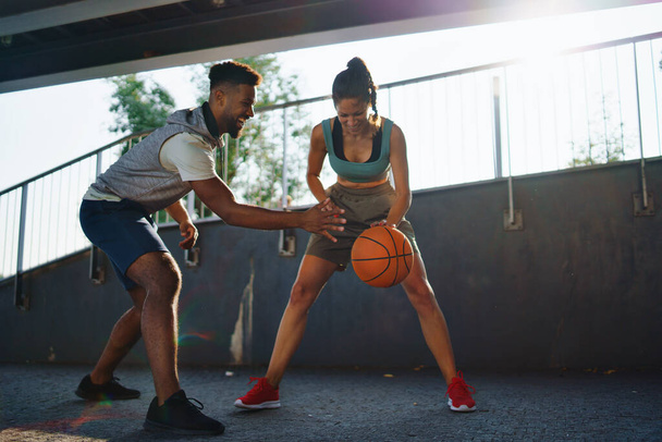 男性と女性の友人は市内で屋外でバスケットボールをプレイ. - 写真・画像