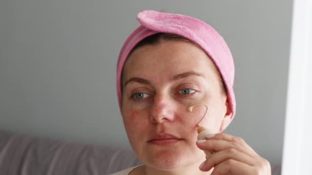 Portrait of young woman applying makeup with sponge - Footage, Video