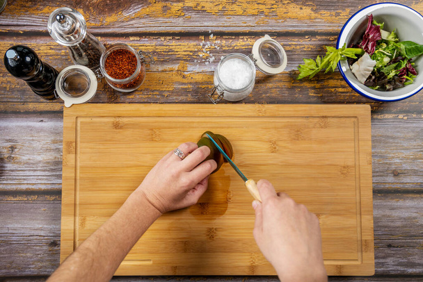 Aus Sicht des Chefs Tomaten auf einem Bambustisch schneiden, um einen Salat mit Salzflocken und Paprika zuzubereiten - Foto, Bild