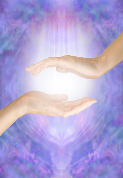 Percepire l'energia proveniente dal chakra della palma - mano aperta che aleggia su un'altra mano aperta con luce bianca tra contro un etereo campo di energia lilla blu con spazio per il testo - Foto, immagini
