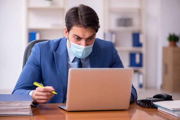 Junger Geschäftsmann arbeitet während der Pandemie im Büro - Foto, Bild
