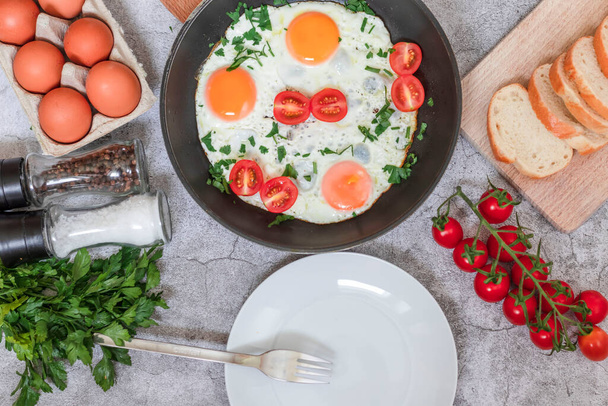 Fried eggs in a frying pan. On a concrete gray background. On the plate - Photo, image