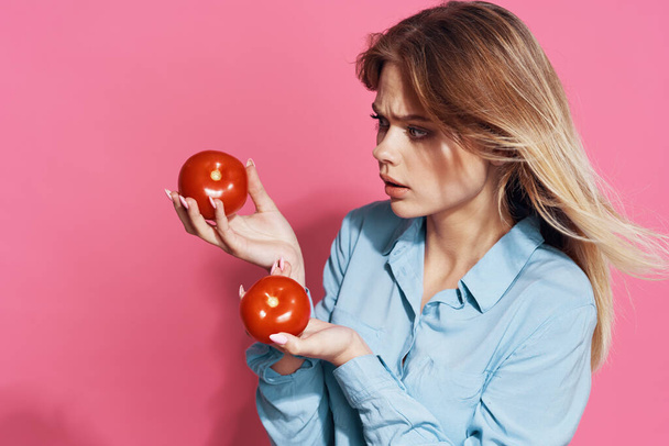 linda chica rubia con tomates en sus manos comida sana fondo rosa - Foto, Imagen
