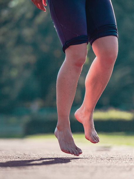 Середнього віку босоніж жінка розігріває м'язи і розтягує ноги на біговій доріжці стадіону. Справжні люди займаються спортом
 - Фото, зображення