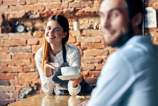 Kellnerin mit einer Tasse Kaffee bedient einen Kunden - Foto, Bild