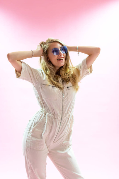 Schöne junge blonde Frau posiert auf rosa Hintergrund  - Foto, Bild