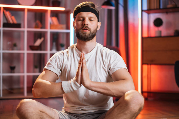 Namaste hareketleriyle lotus pozisyonunda meditasyon yapan adam. - Fotoğraf, Görsel
