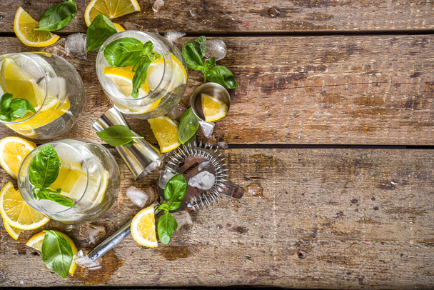 Boozy lemon basil lemonade, with fresh basil leaves, lemons and crushed ice, rustic wooden background copy space - Фото, зображення