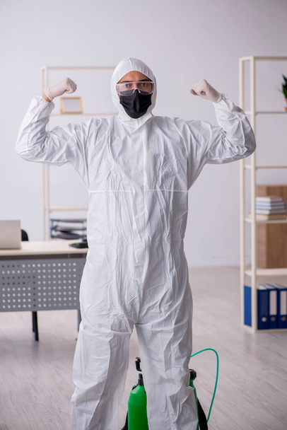 Young male contractor disinfecting office during pandemic - Фото, зображення