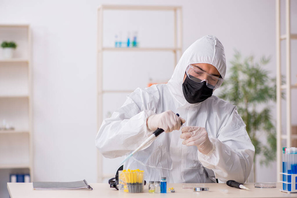 Jovem químico do sexo masculino que trabalha no laboratório durante a pandemia - Foto, Imagem