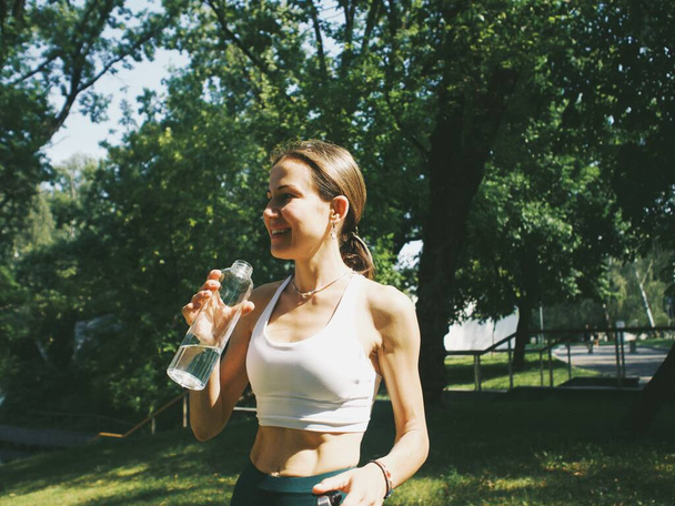 młoda kobieta pijąca wodę po treningu w parku - Zdjęcie, obraz
