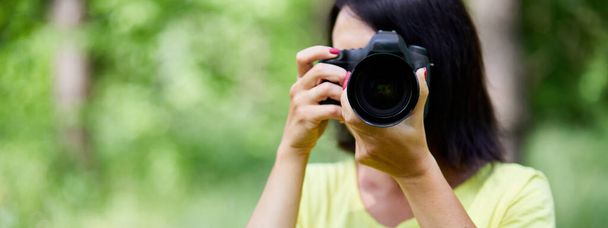 カメラの屋外で彼女の顔を覆う女性写真家の肖像画のバナー写真を撮る,世界の写真家の日,手にカメラを持つ若い女性. - 写真・画像