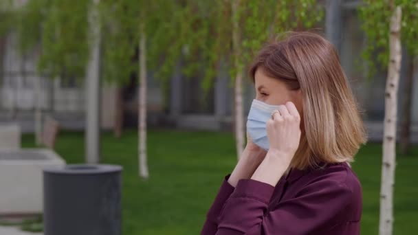 Business woman puts on face medical mask to protect sitting on bench park city. Healthcare. Safety measures concept. Business lady safe care. - Footage, Video