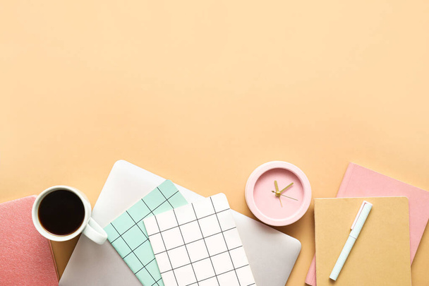 Relógio despertador com material de escritório, xícara de café e laptop no fundo de cor - Foto, Imagem