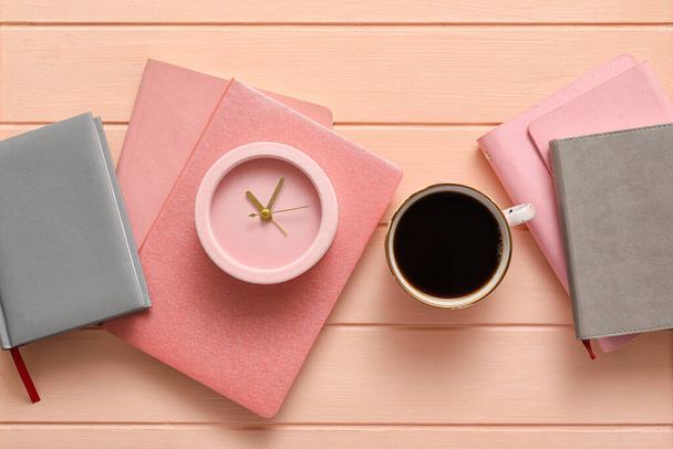Будильник с ноутбуками и чашкой кофе на фоне цвета дерева - Фото, изображение