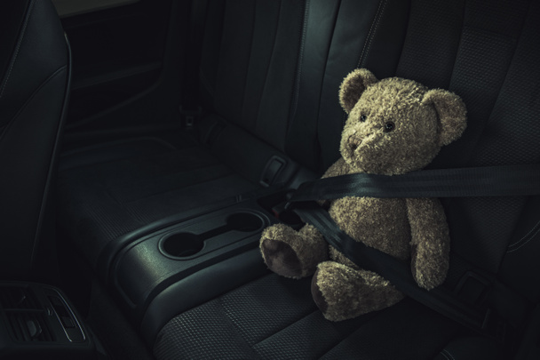Tema de segurança de transporte de carro de criança. Teddy Bear em um banco de trás com cinto de segurança apertado. - Foto, Imagem