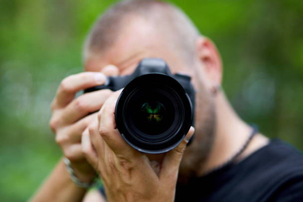 Portrait d'un photographe masculin couvrant son visage avec l'appareil photo en plein air photo, Journée mondiale du photographe, Jeune homme avec un appareil photo à la main. - Photo, image