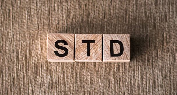 STD - Sexually transmitted diseases, word written on wooden blocks on a brown background. - Foto, imagen