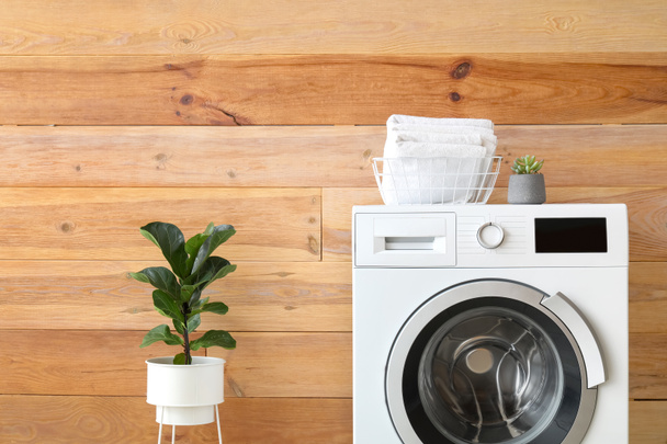 木製の壁の近くにタオルと現代の洗濯機 - 写真・画像