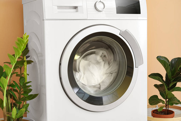 Máquina de lavar roupa moderna com lavanderia perto da parede de cor - Foto, Imagem
