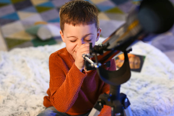 Kleine jongen met telescoop kijkend naar sterren in de avond - Foto, afbeelding