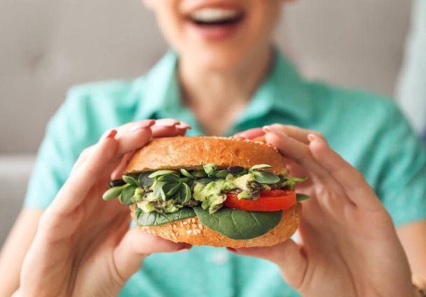 Mujer joven con sabrosa hamburguesa vegana en casa, primer plano - Foto, Imagen
