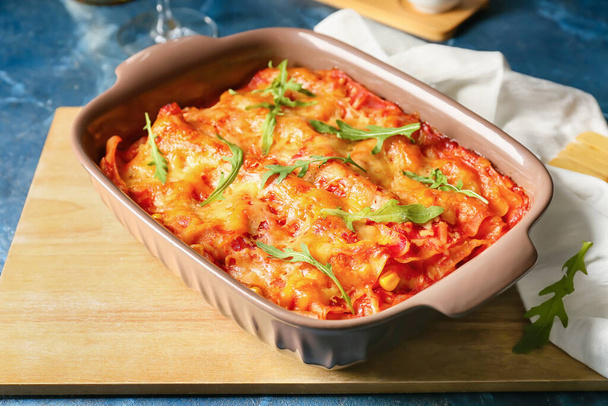 Baking dish with tasty tomato lasagna on color background - 写真・画像