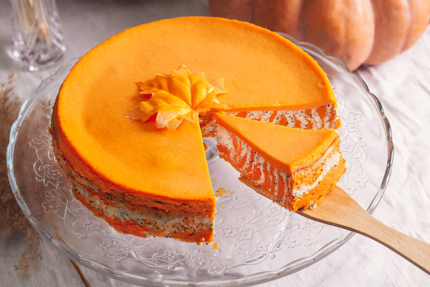Homemade cottage cheese and pumpkin casserole with poppy seeds and orange and cut piece on a glass stand and pumpkins. - Photo, Image