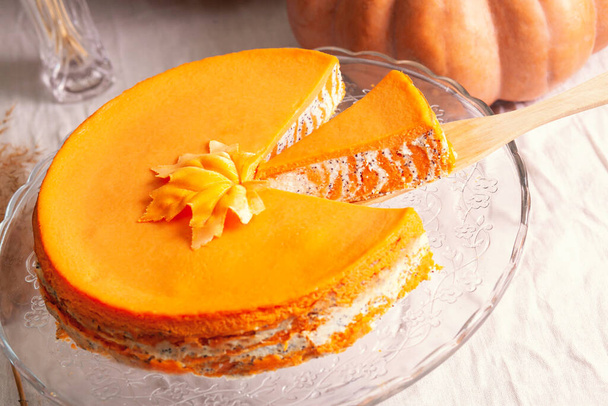 Homemade cottage cheese and pumpkin casserole with poppy seeds and orange and cut piece on a glass stand and pumpkins. - Φωτογραφία, εικόνα