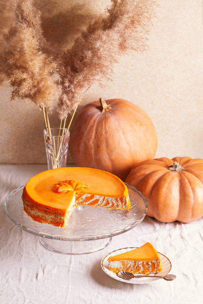 Homemade cottage cheese and pumpkin casserole with poppy seeds and orange and cut piece on a glass stand and pumpkins. - Φωτογραφία, εικόνα