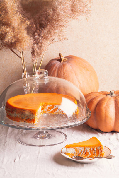 Homemade cottage cheese and pumpkin casserole with poppy seeds and orange and cut piece on a glass stand and pumpkins. - Foto, Imagem