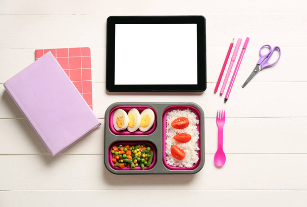 Lounas laatikko maukasta ruokaa, tabletti tietokone ja paperitavarat valkoinen puinen tausta - Valokuva, kuva