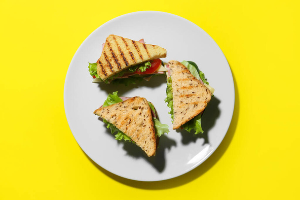 Πιάτο με νόστιμα σάντουιτς στο φόντο χρώμα - Φωτογραφία, εικόνα