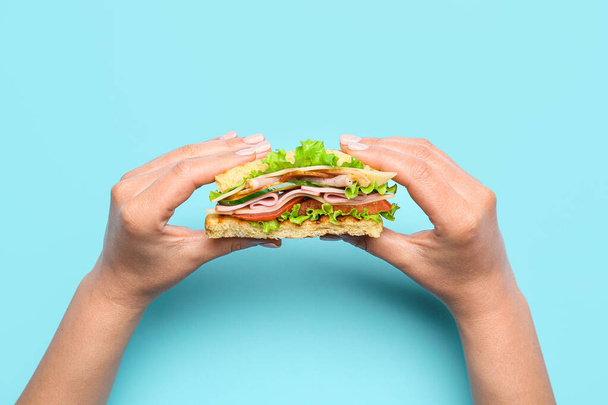 Female hands with tasty sandwich on color background - Photo, Image