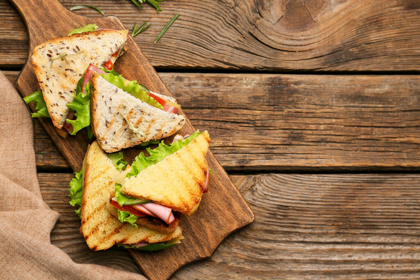 Board with tasty sandwiches on wooden background - Foto, afbeelding