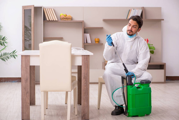 Contratista masculino joven desinfectando en casa - Foto, imagen