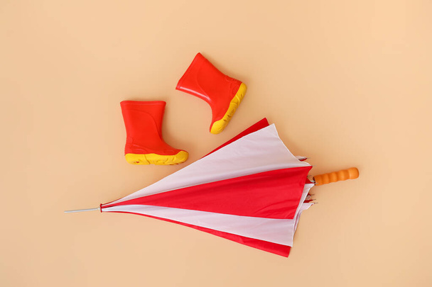 Stylish umbrella with gumboots on color background - Photo, Image