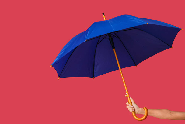 Female hand with open umbrella on color background - Foto, afbeelding