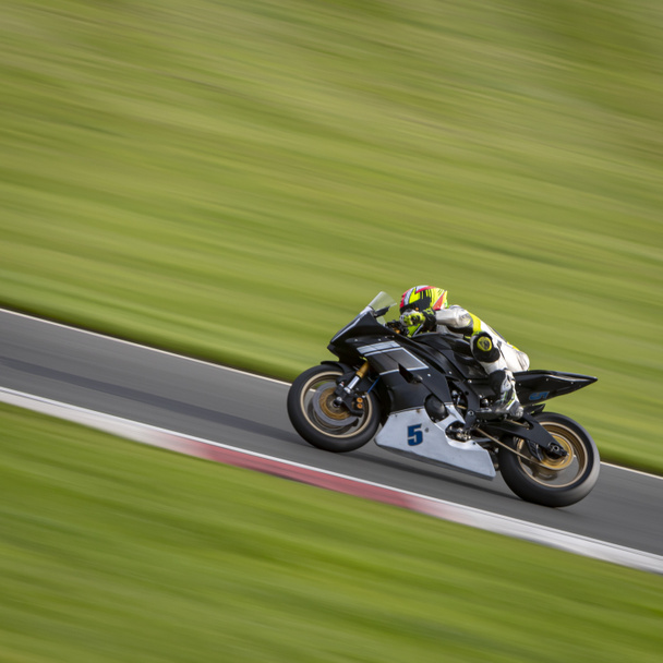 панорамный снимок гоночного мотоцикла, когда он обходит трассу. - Фото, изображение