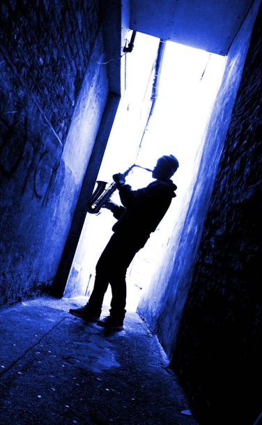  青い光の中に置かれたサックス奏者のシルエット - 写真・画像