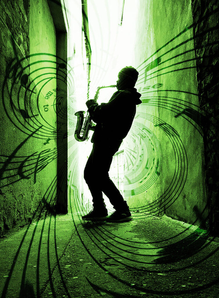音楽と緑の光に対してシルエットストリートサックスプレーヤーは感動  - 写真・画像