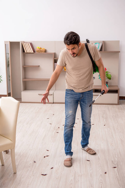Молодий чоловік знищує тарганів вдома
 - Фото, зображення