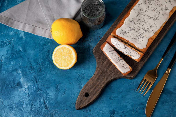 Ξύλινη σανίδα με νόστιμο κέικ σπόρων παπαρούνας και μαχαιροπίρουνα στο τραπέζι - Φωτογραφία, εικόνα