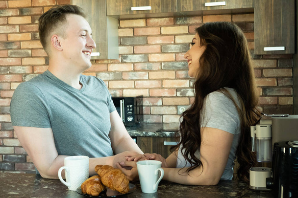 Young couple having breakfast in modern kitchen and talking, concept of happiness and daily life. - Valokuva, kuva