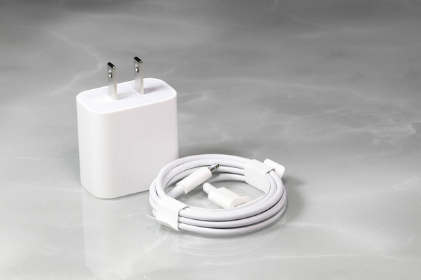 Weißes Ladegerät und weißes USB-Kabel auf weißem Hintergrund, Neues Ladegerät und Kabelanschluss für Geräte isoliert auf weißem Hintergrund. Das Konzept der Aufladetechnologie für Mobiltelefone.  - Foto, Bild